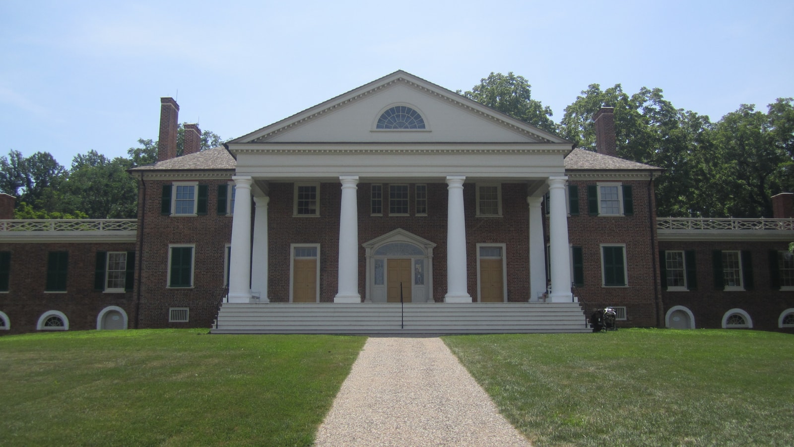 Front facade and columned portico of James Madison's Montpelier in bright daylight.
