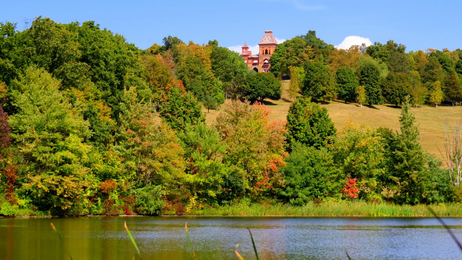 Olana's historic house seen across the estate lake and autumn landscape.