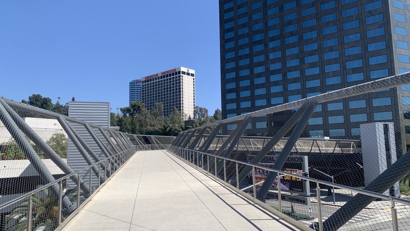 Universal City pedestrian bridge toward Universal Studios Hollywood with nearby Universal City hotels.