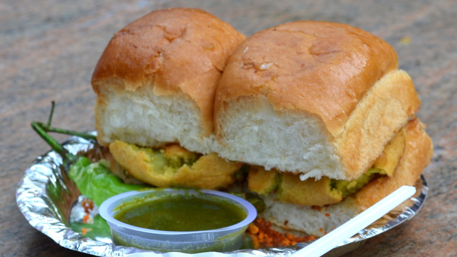 Vada pav with visible potato fritters, green chilli and chutney