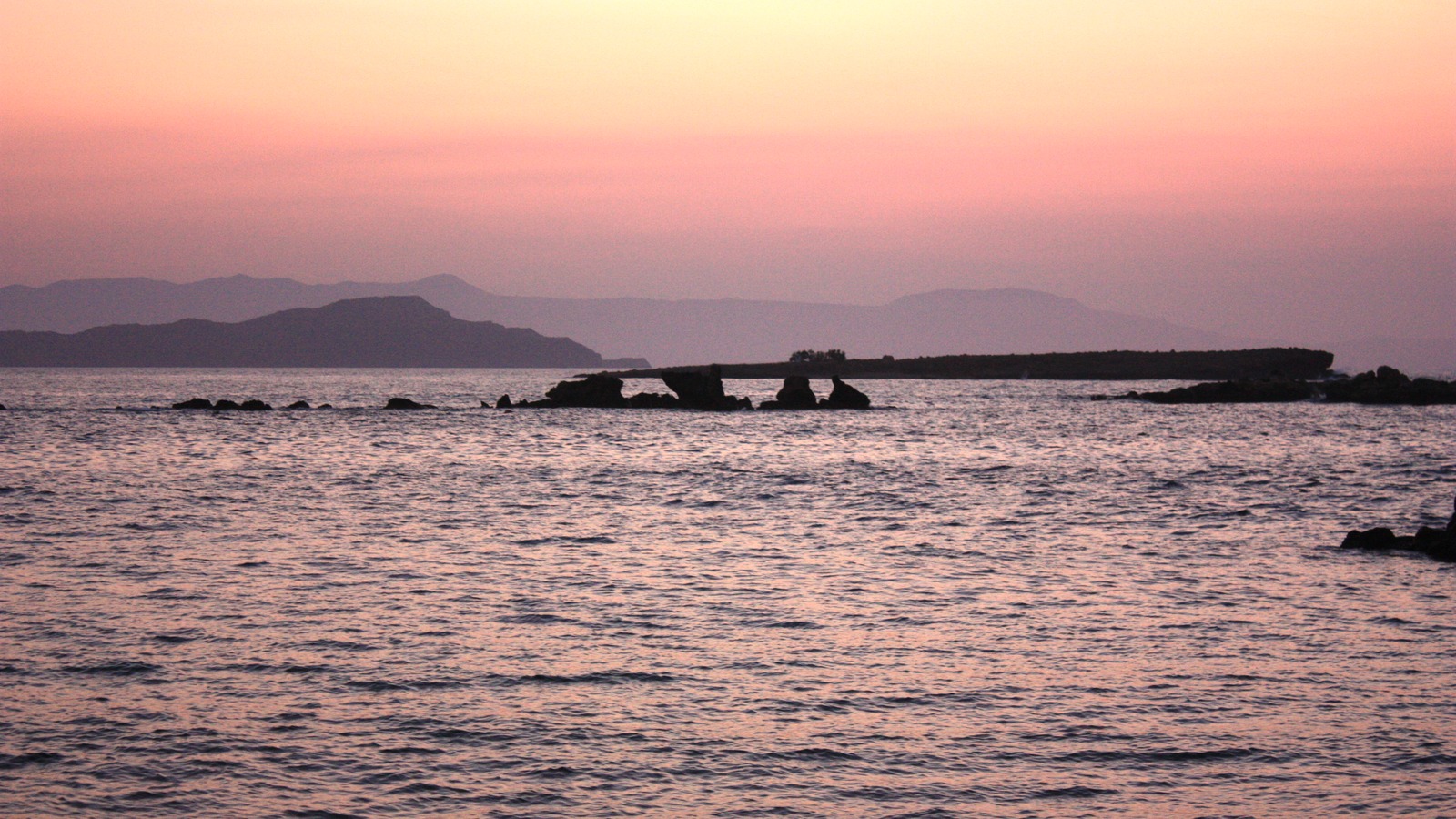 Nea Chora beachfront and offshore islet at sunset in Chania, Crete