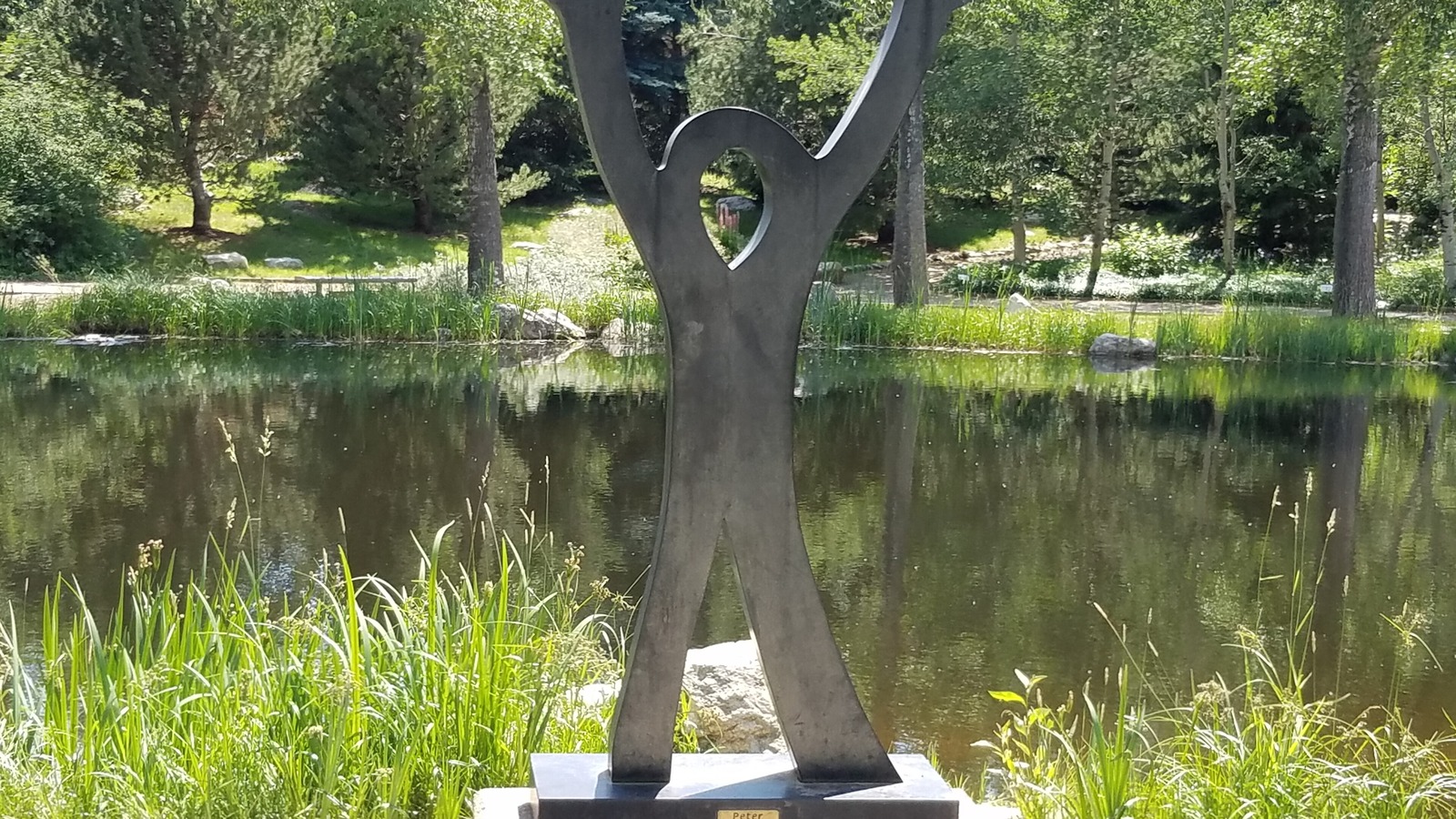 A pond and sculpture at Yampa River Botanic Park near the central Pine Grove corridor