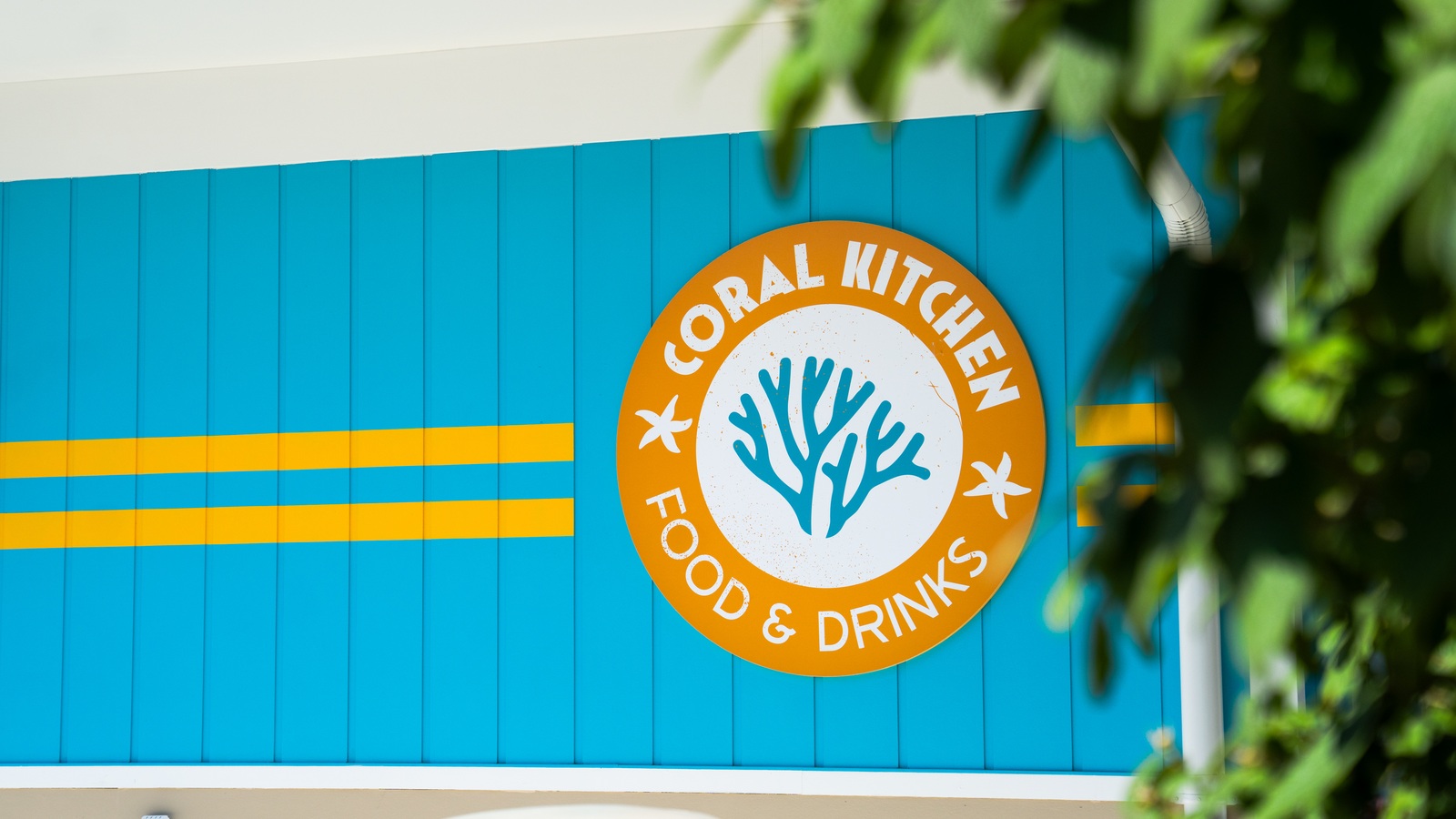 Round orange Coral Kitchen sign on a turquoise exterior wall at Zoombezi Bay