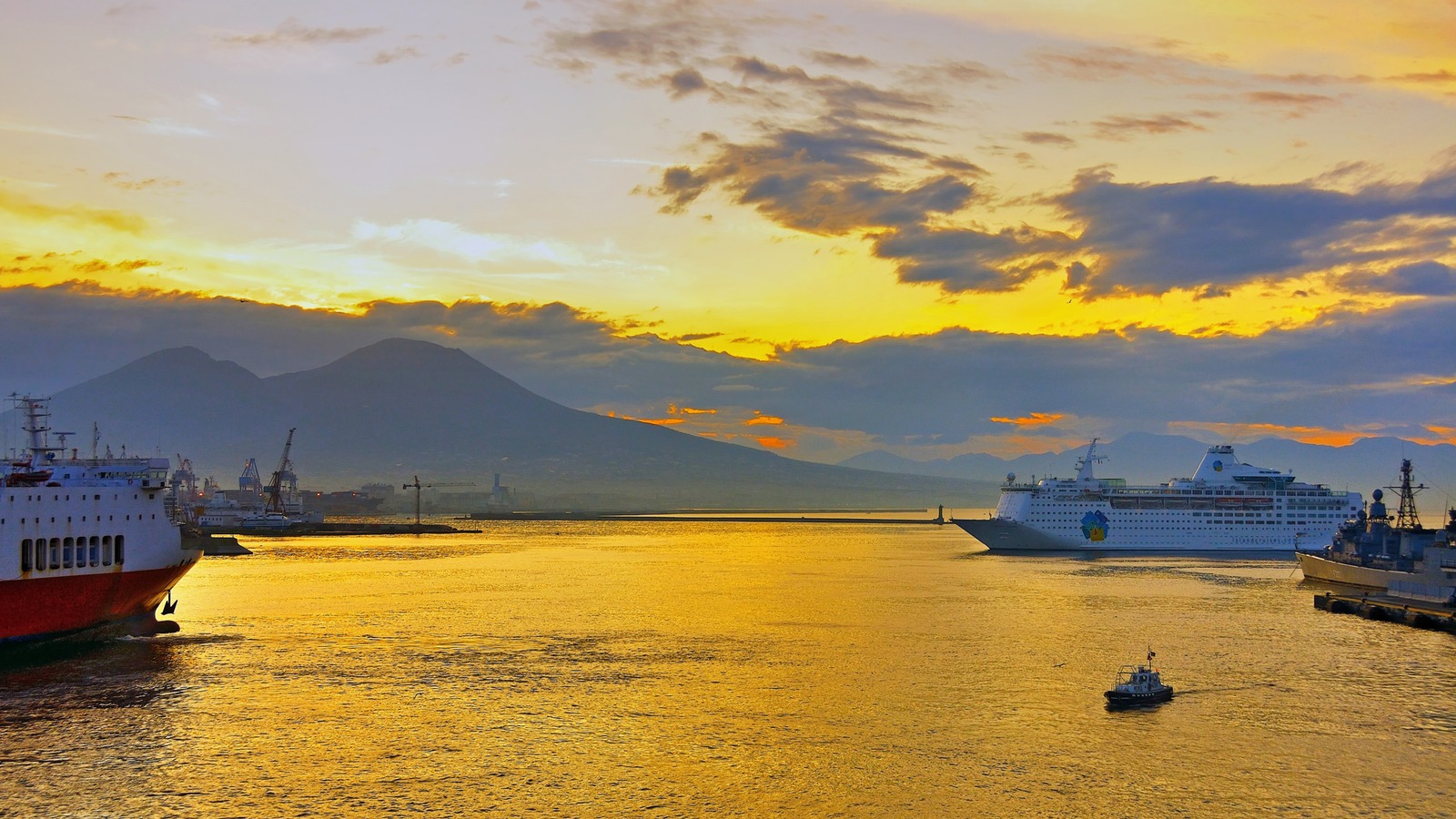 Cruise ship and ferry in the harbor of Naples at dawn with Mount Vesuvius in the background
