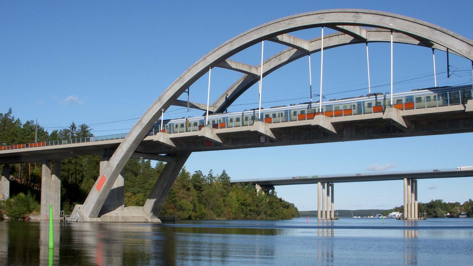 A Stockholm commuter train crossing the Stäket arch bridge on the Mälarbanan line over calm water