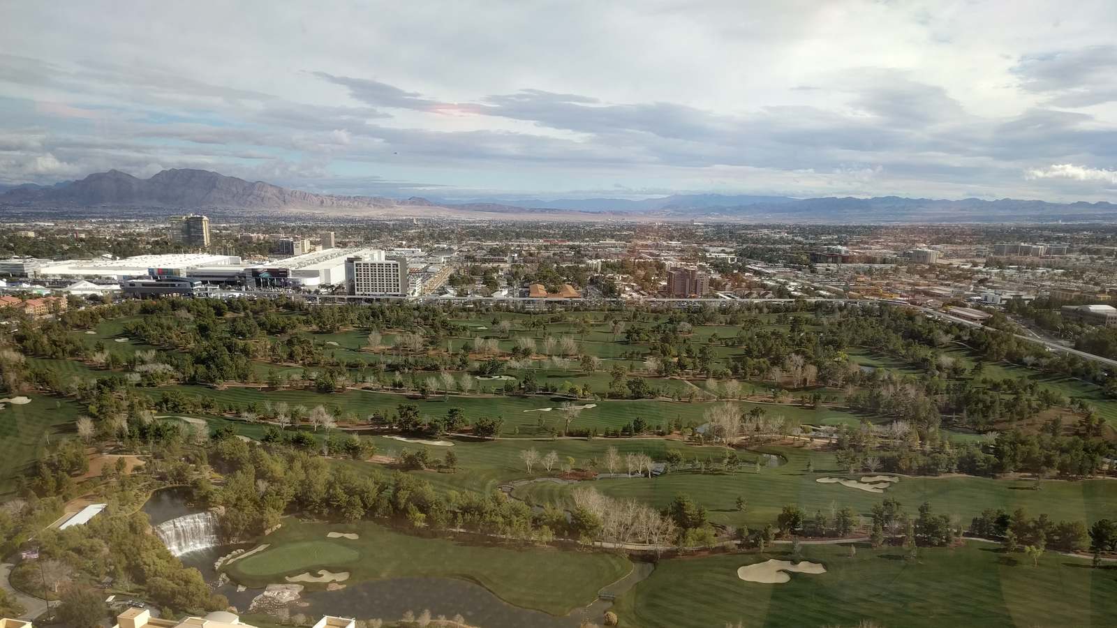 Aerial view over the Wynn Las Vegas golf course with its waterfall and fairways and mountains beyond, in an earlier photograph before the new clubhouse opened.