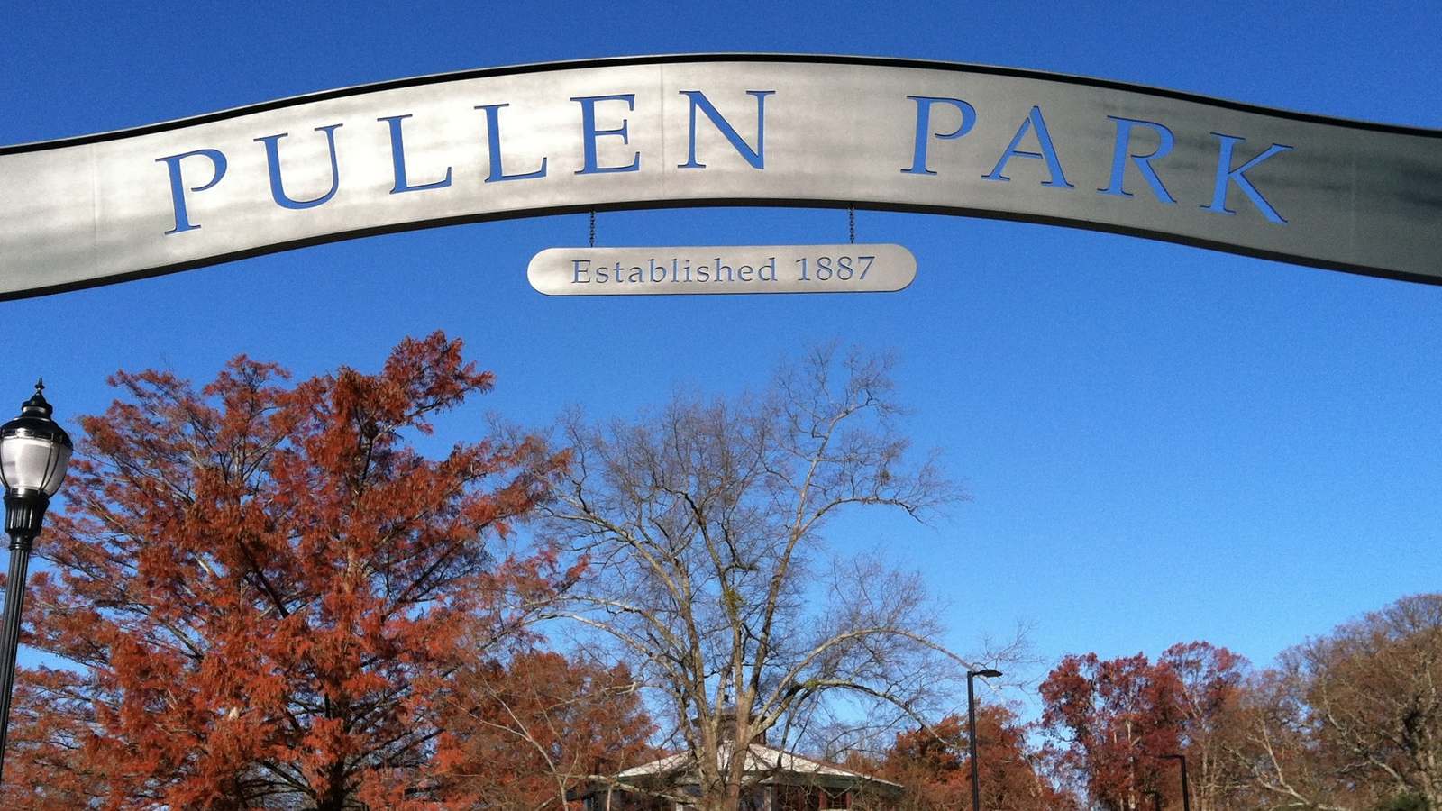 Pullen Park entrance arch reading Established 1887 against a blue autumn sky