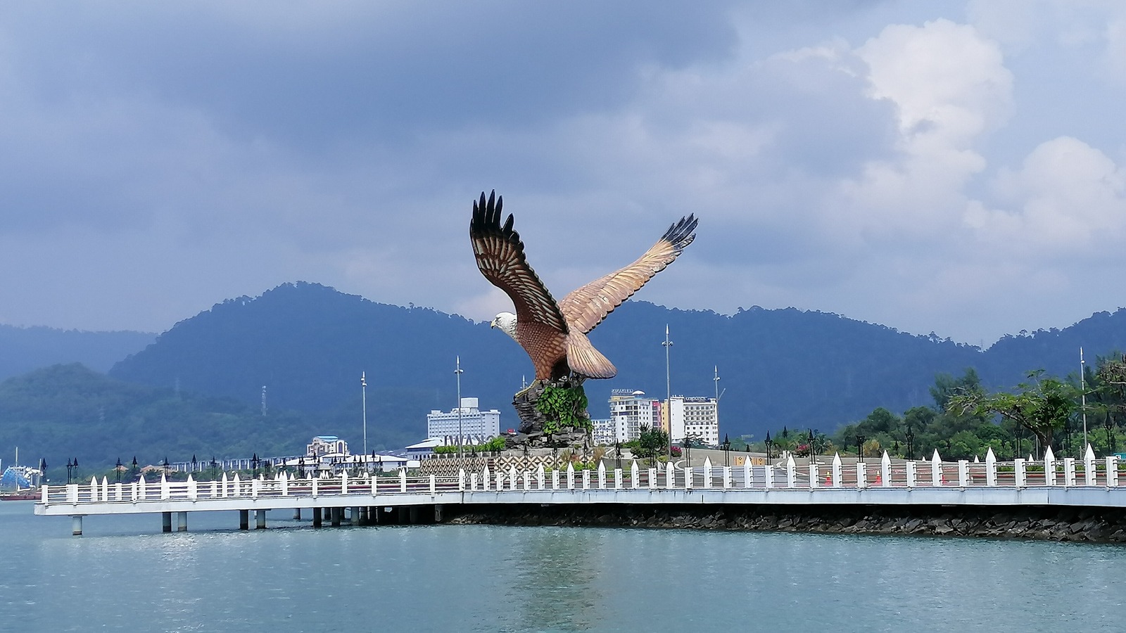 The Eagle Square eagle statue on the Kuah waterfront in Langkawi with forested hills behind