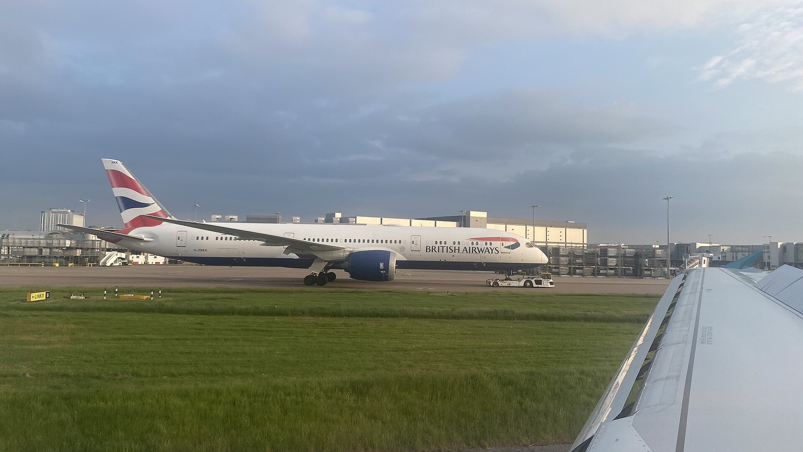 A British Airways Boeing 787-9 is towed on the apron at London Heathrow beside a wing tip