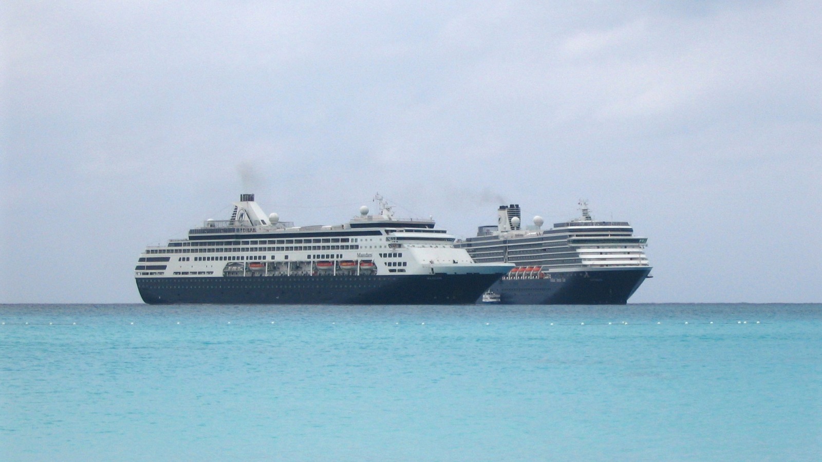 Two Holland America cruise ships anchored off the turquoise water of Half Moon Cay in the Bahamas
