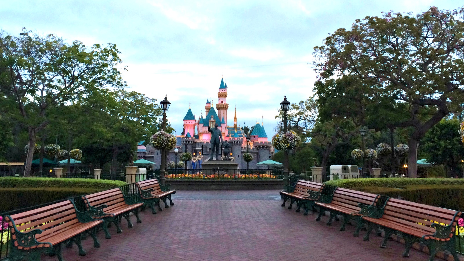 Sleeping Beauty Castle at Disneyland in Anaheim, seen at dusk from the hub with the Partners statue in the foreground