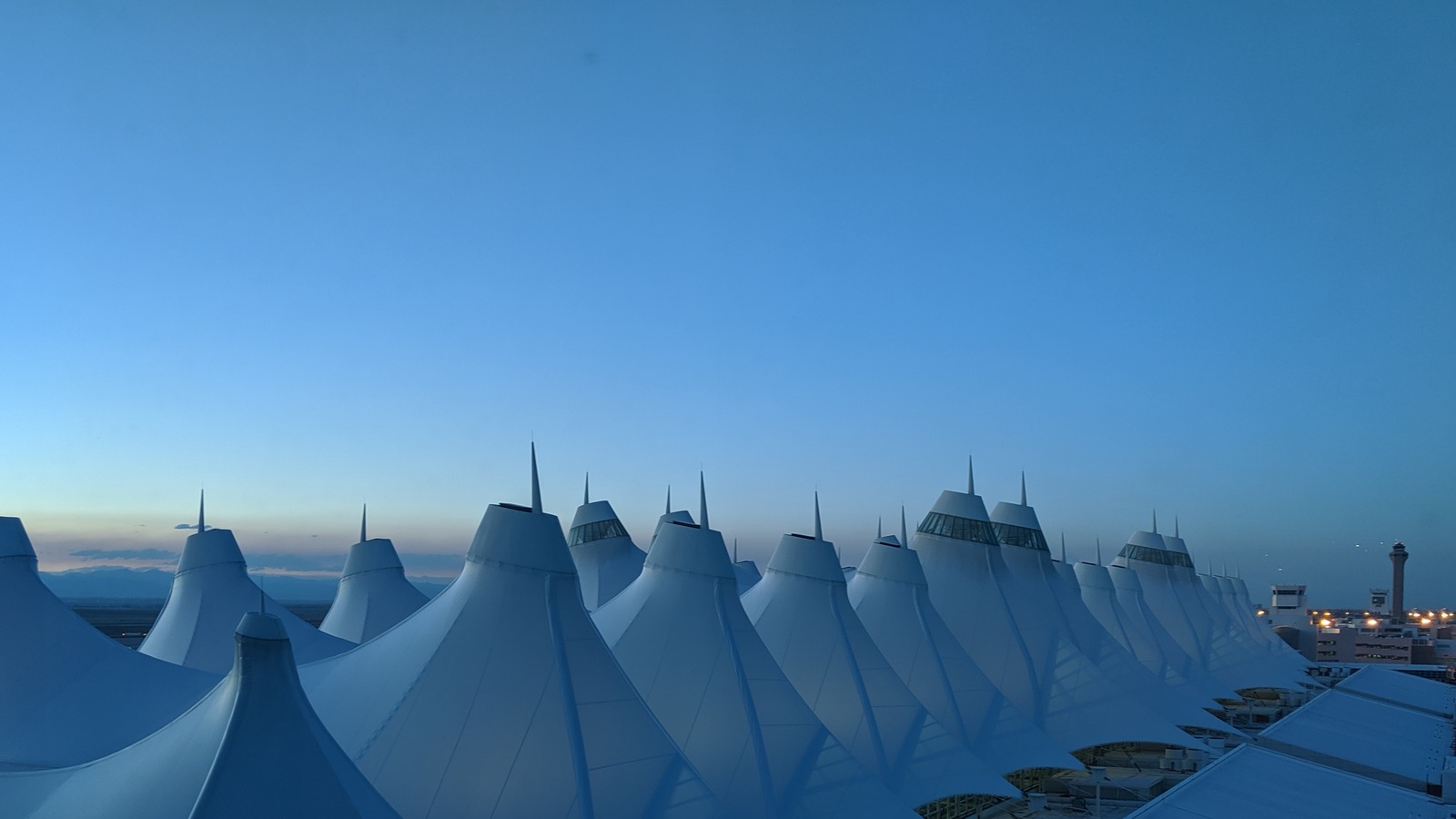 Denver International Airport main terminal exterior at dusk, the airport served by the new nearby Everhome Suites hotel