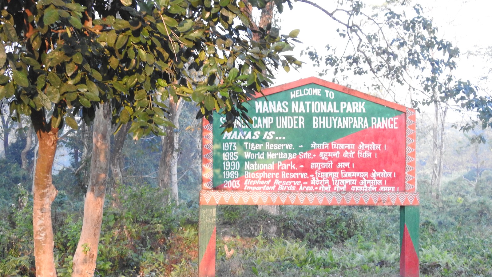 Welcome sign for Manas National Park under the Bhuyanpara Range, Assam, with forest behind it