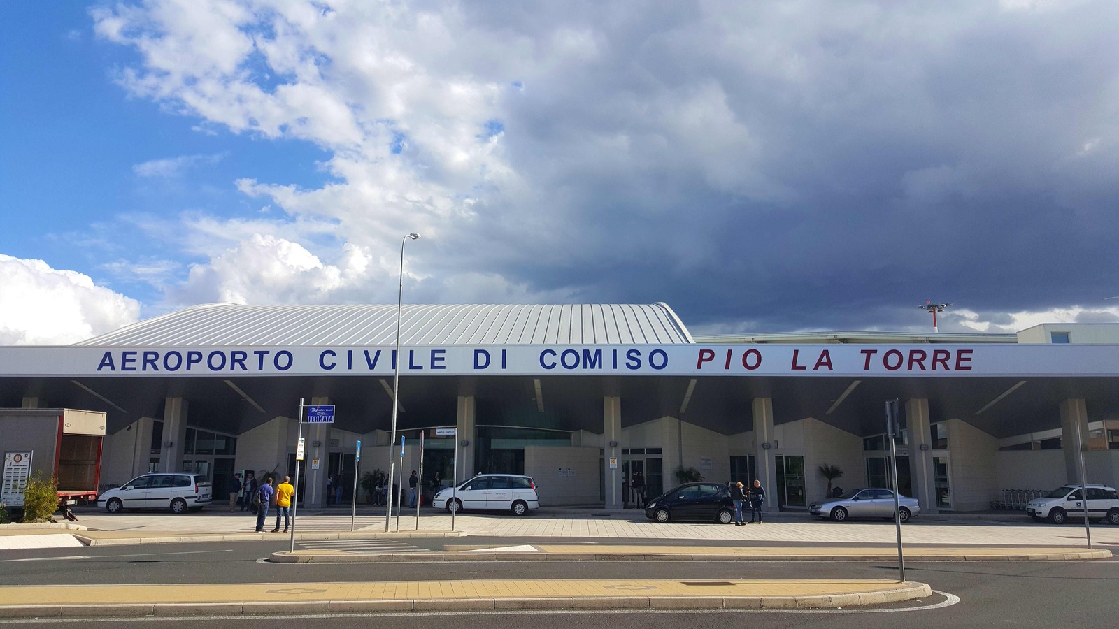 Exterior view of Comiso Airport terminal and apron in Sicily under a clear sky