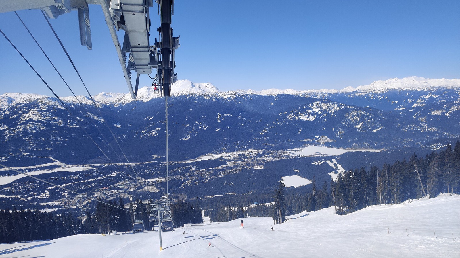 A gondola line and snowy ski run above Whistler, British Columbia, with mountains and the valley beyond