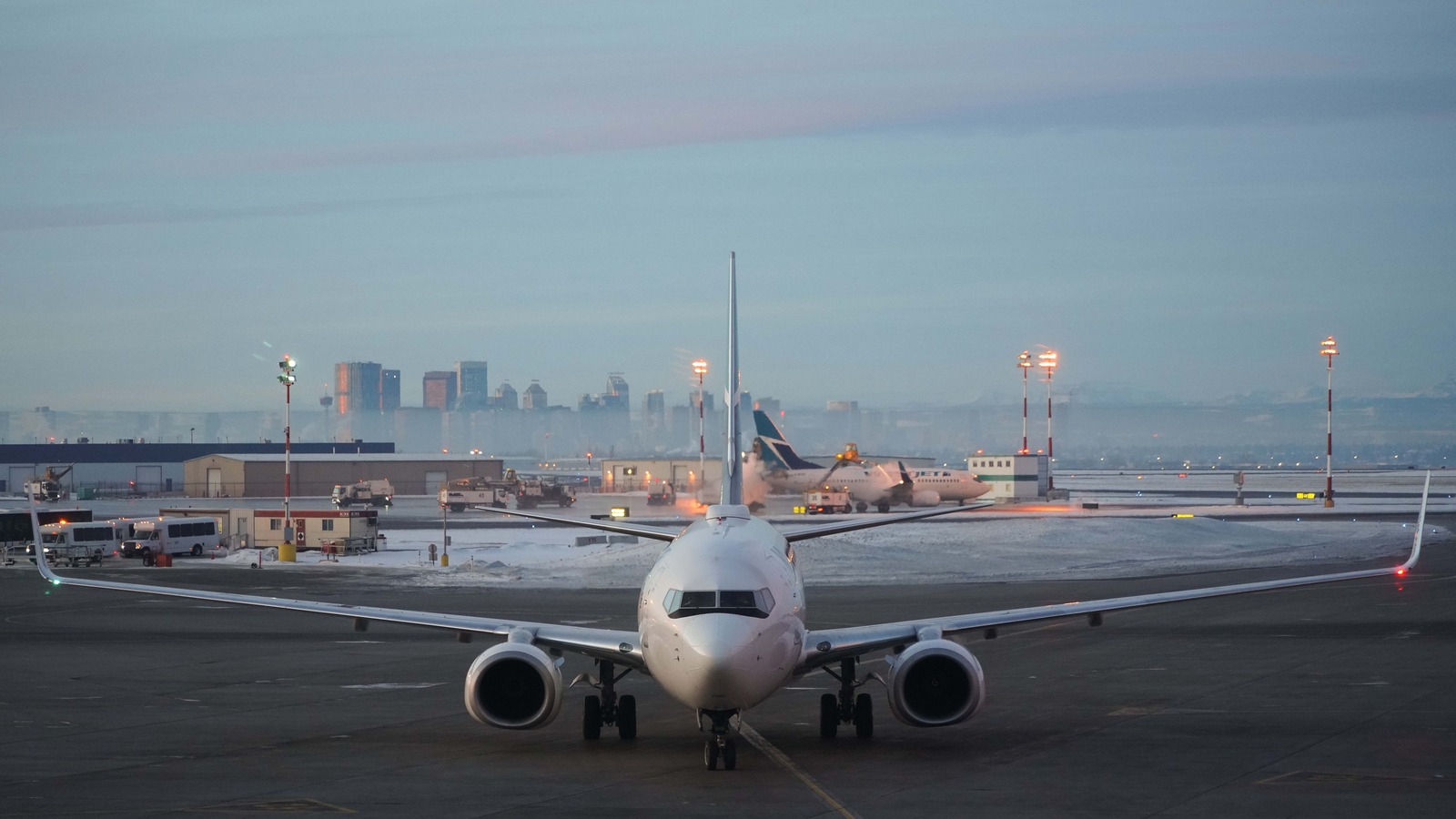 WestJet Boeing 737 aircraft at Calgary International Airport with the Calgary skyline in the distance