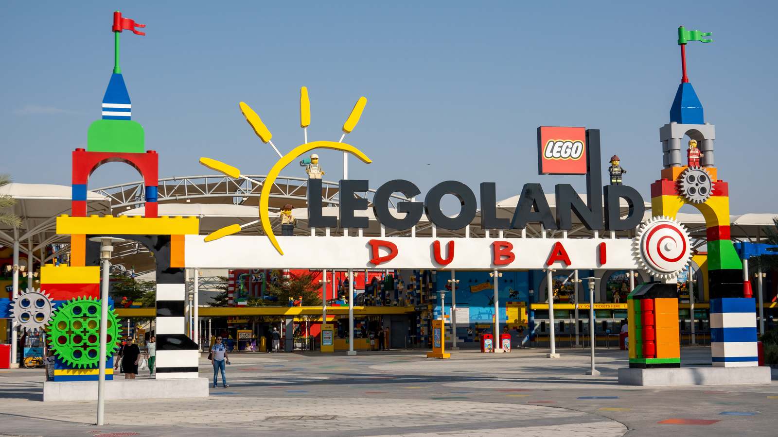 The LEGOLAND Dubai entrance arch with LEGO brick towers and a LEGOLAND Dubai sign under a clear sky