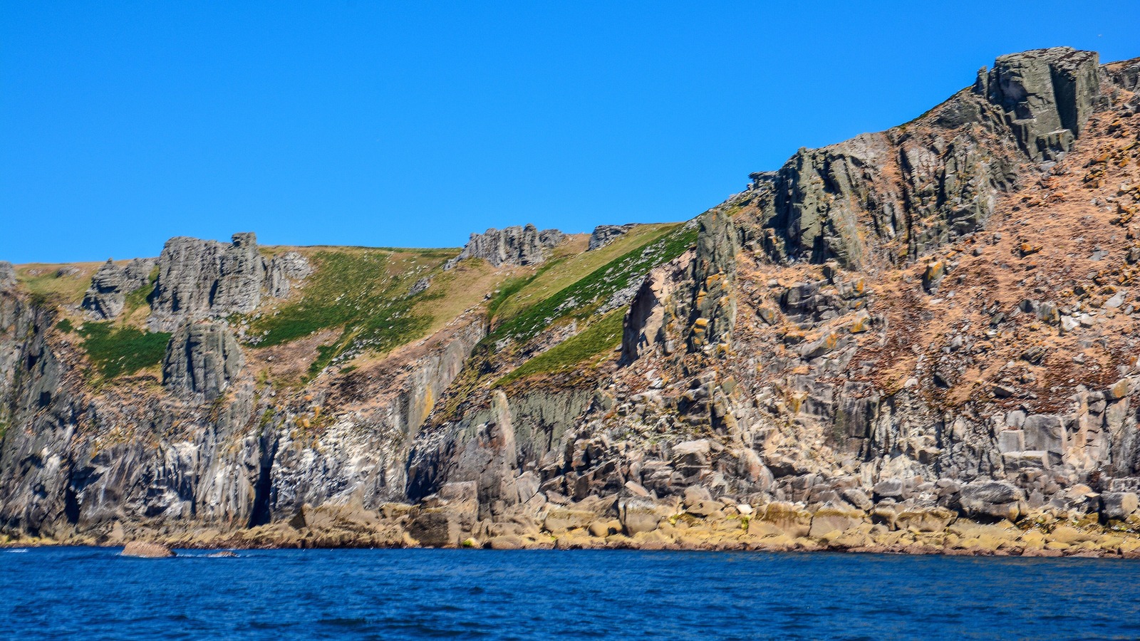 Granite cliffs on the coast of Lundy Island seen from the sea in a 2018 photo