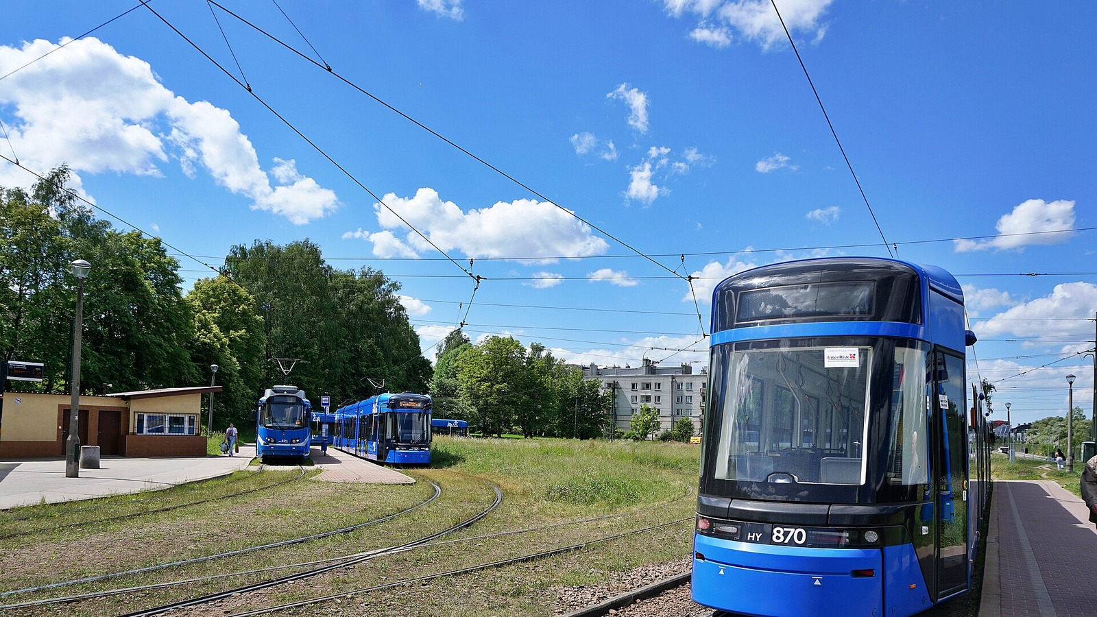 Blue Kraków trams standing at the Mistrzejowice tram loop under a bright sky