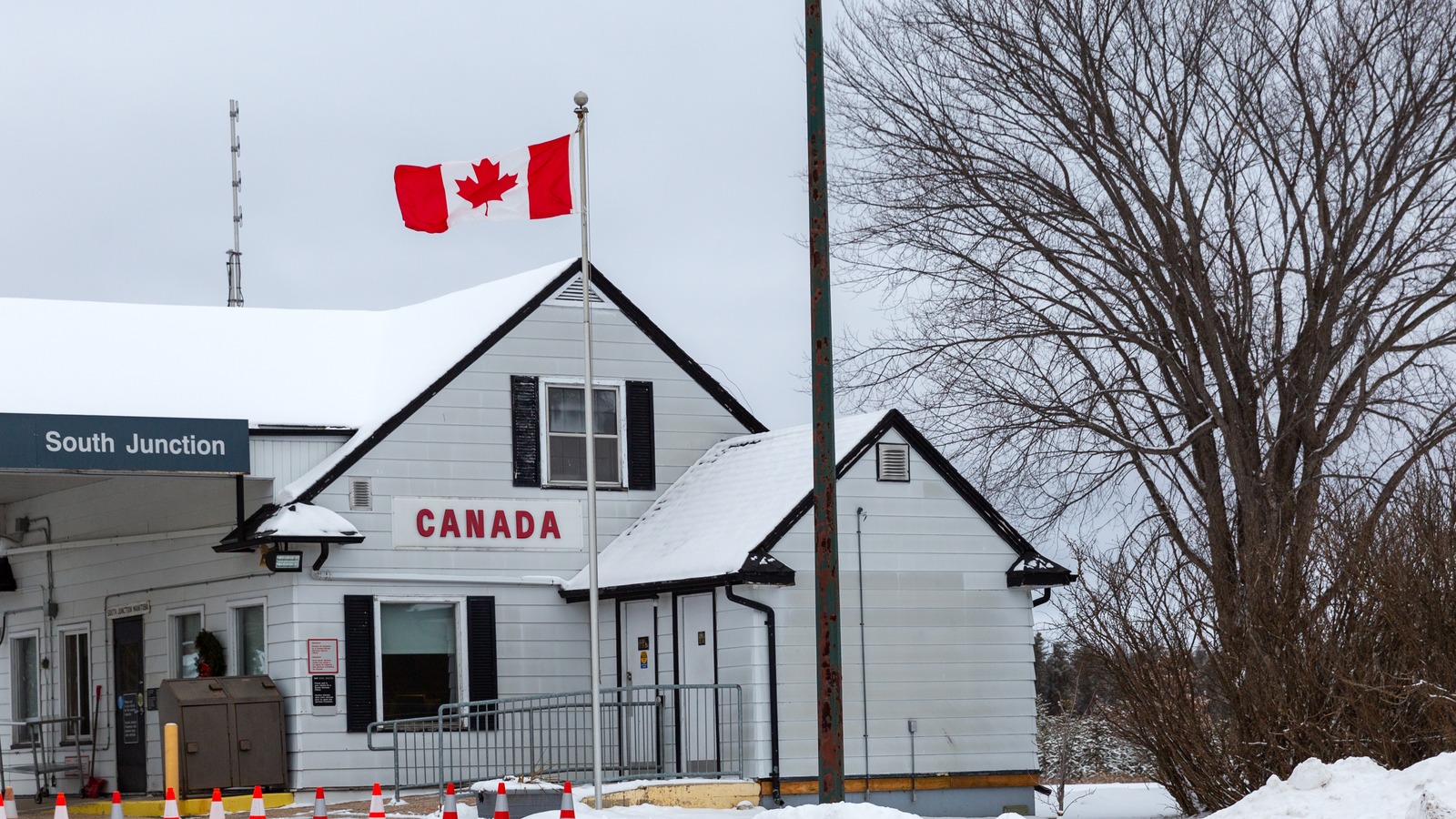 The snow covered South Junction port of entry building in Manitoba with a Canada sign and Canadian flag