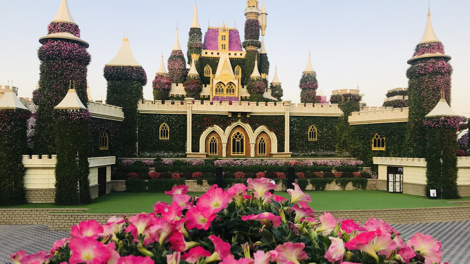 Dense colorful floral displays and shaped topiary structures at Dubai Miracle Garden in daylight