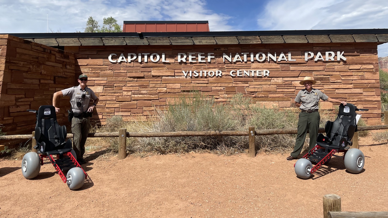 Two all-terrain wheelchairs outside Capitol Reef National Park Visitor Center with NPS rangers, photographed August 27, 2026