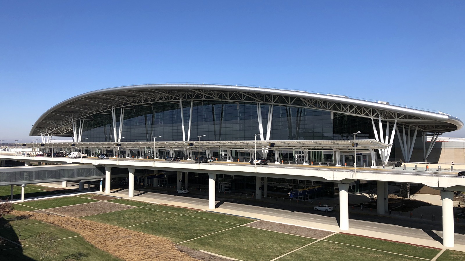 Daylight exterior of the Colonel H. Weir Cook Terminal at Indianapolis International Airport, with the curved roof and upper roadway.