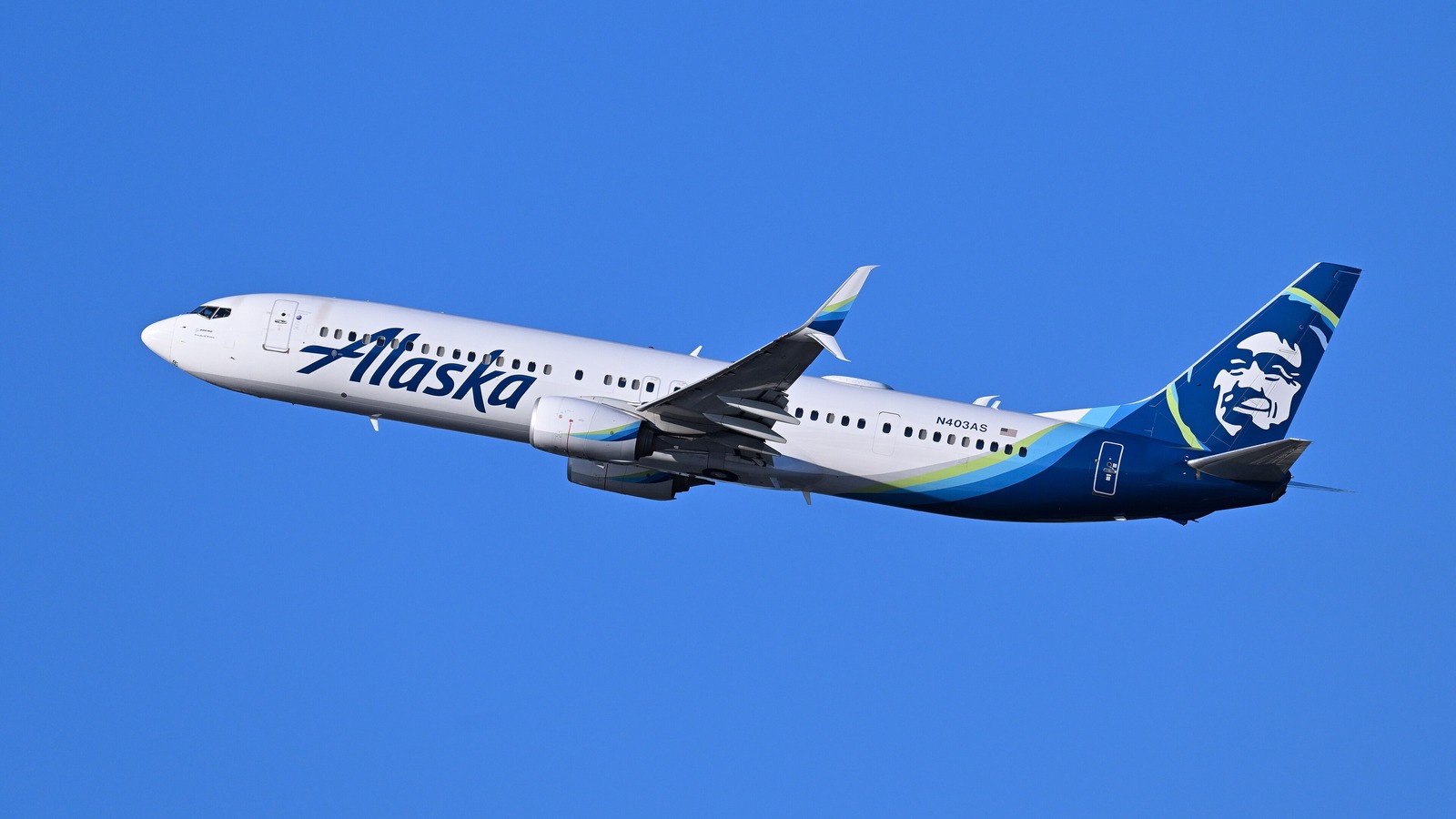 An Alaska Airlines Boeing 737-900ER climbing against a clear blue sky
