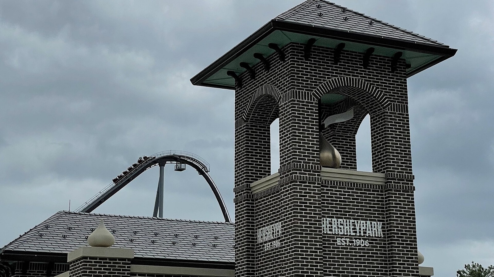 Brick Hersheypark entrance tower with the Candymonium coaster lift hill rising behind it