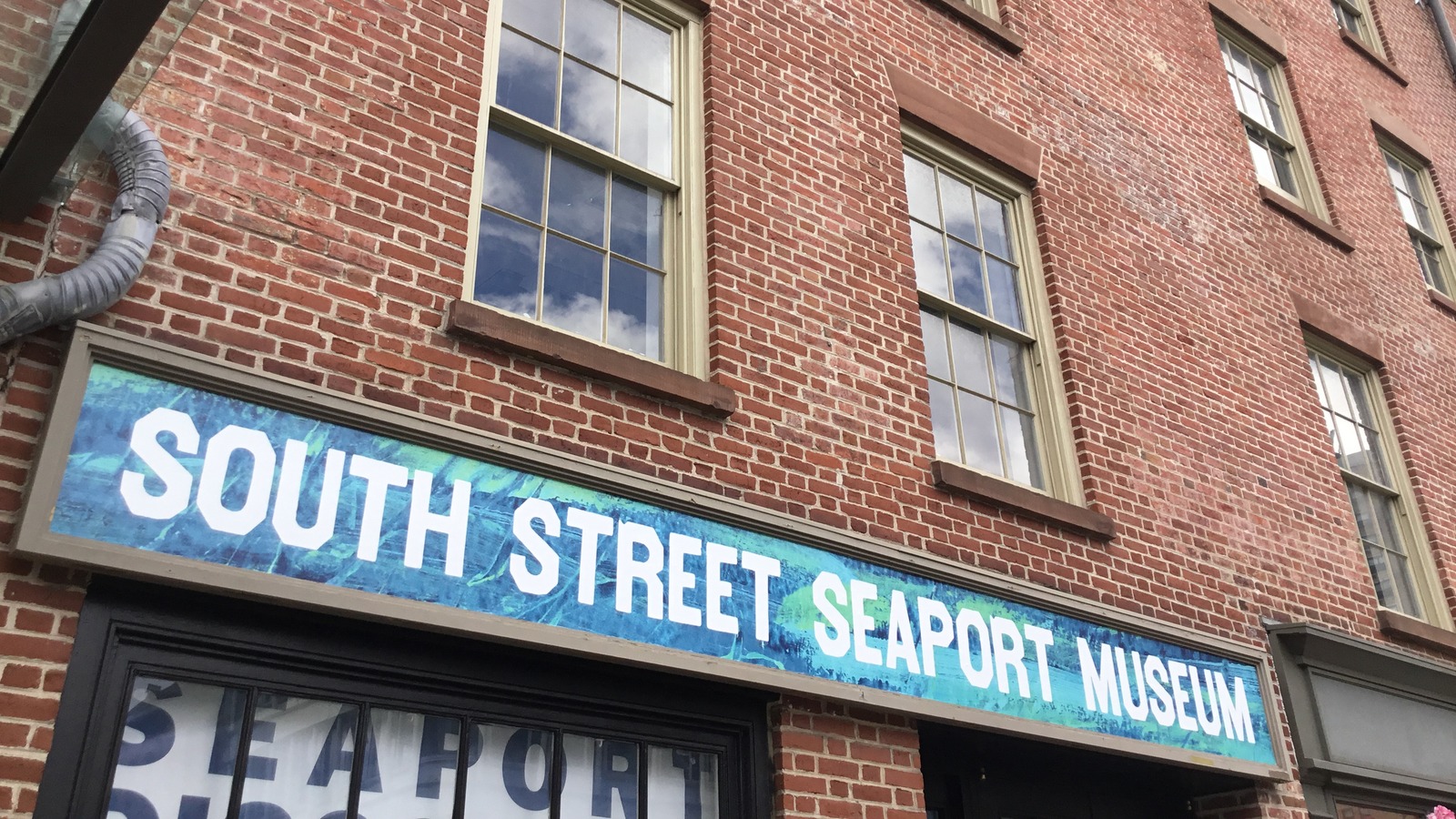 Brick facade and blue sign of the South Street Seaport Museum in Lower Manhattan