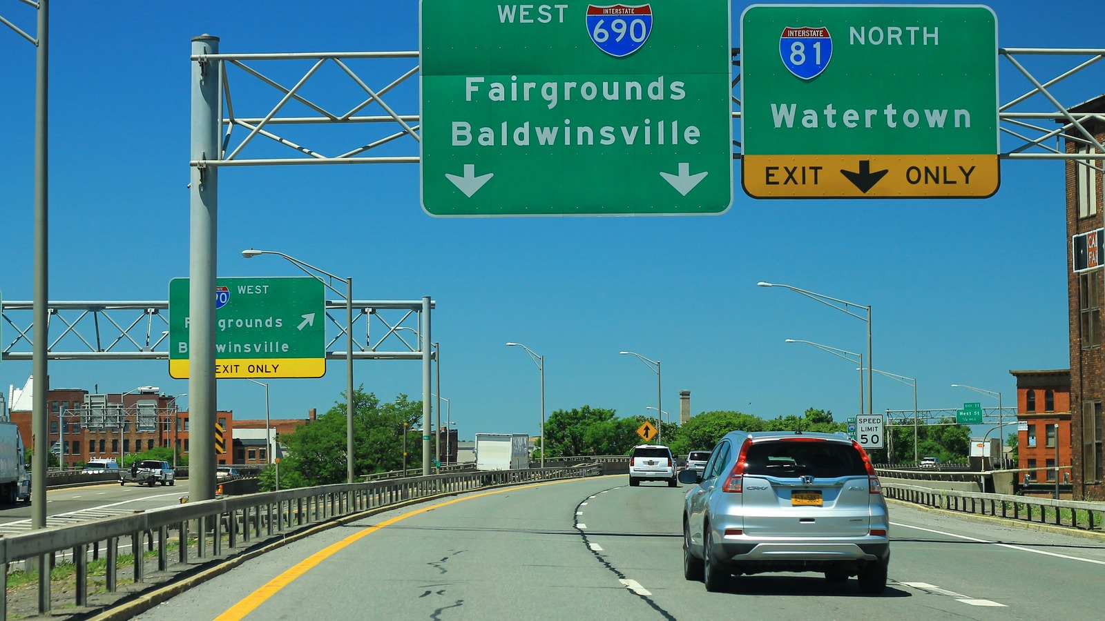 Westbound I-690 in Syracuse approaching the Interstate 81 north exit, with overhead signs for Fairgrounds and Baldwinsville