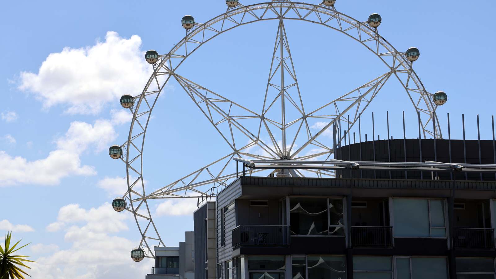 The Melbourne Star observation wheel above buildings in Docklands, Melbourne, under a blue sky