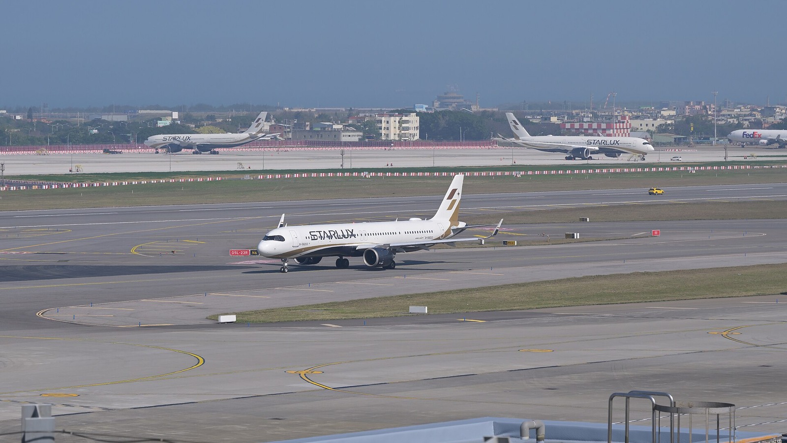 Starlux Airlines Airbus A321neo taxiing at Taipei Taoyuan International Airport with two Starlux widebodies behind