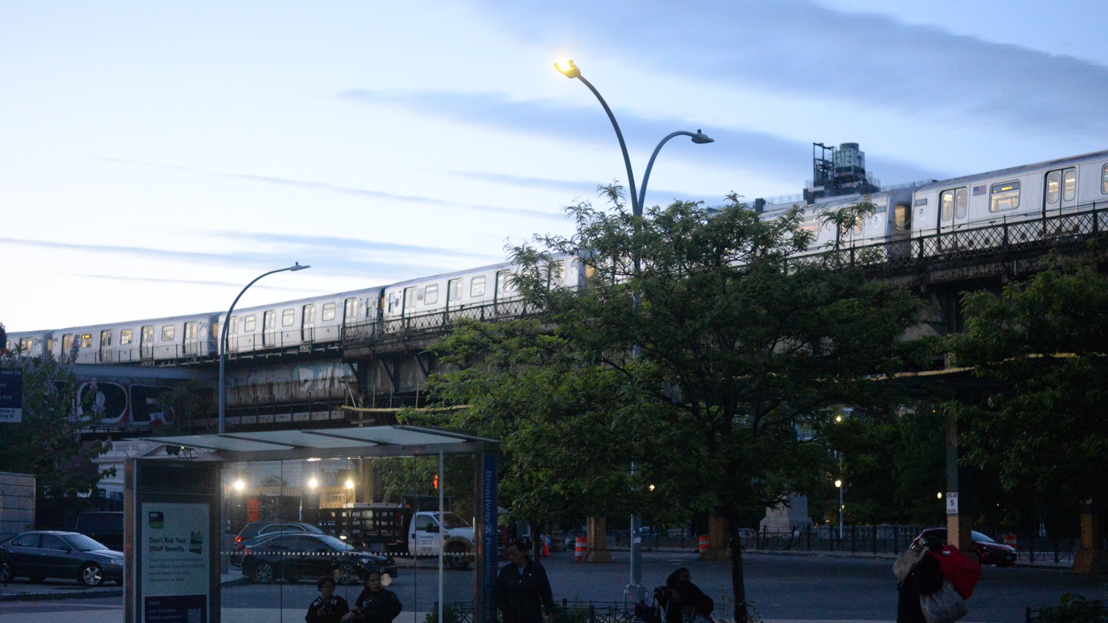 A J train leaving Marcy Avenue toward the Williamsburg Bridge at dusk, photographed May 7, 2026; historical corridor context, not M service or October switch work