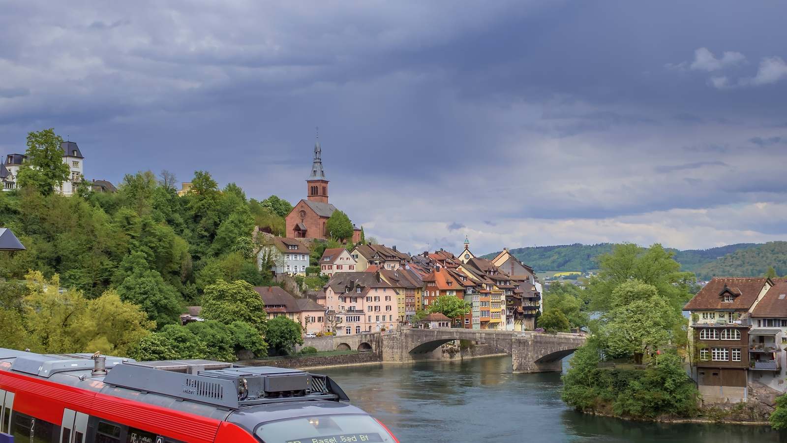 Hochrheinbahn regional train bound for Basel Bad Bf above the Rhine at Laufenburg, with the old town and bridge behind