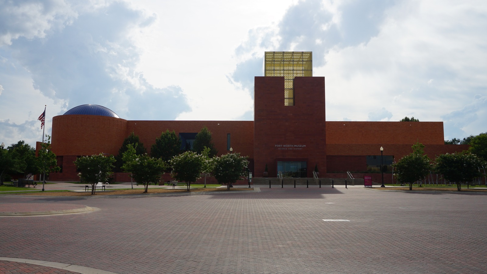 Brick exterior of the Fort Worth Museum of Science and History with its blue planetarium dome and gold tower under a bright sky