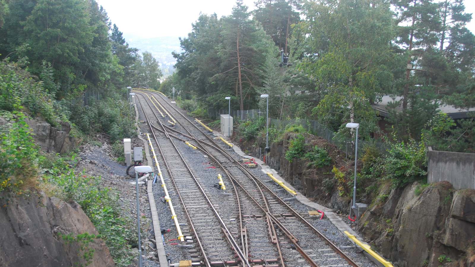 Double metro tracks and switches running downhill through woodland at Holmenkollen station on Oslo T-bane line 1