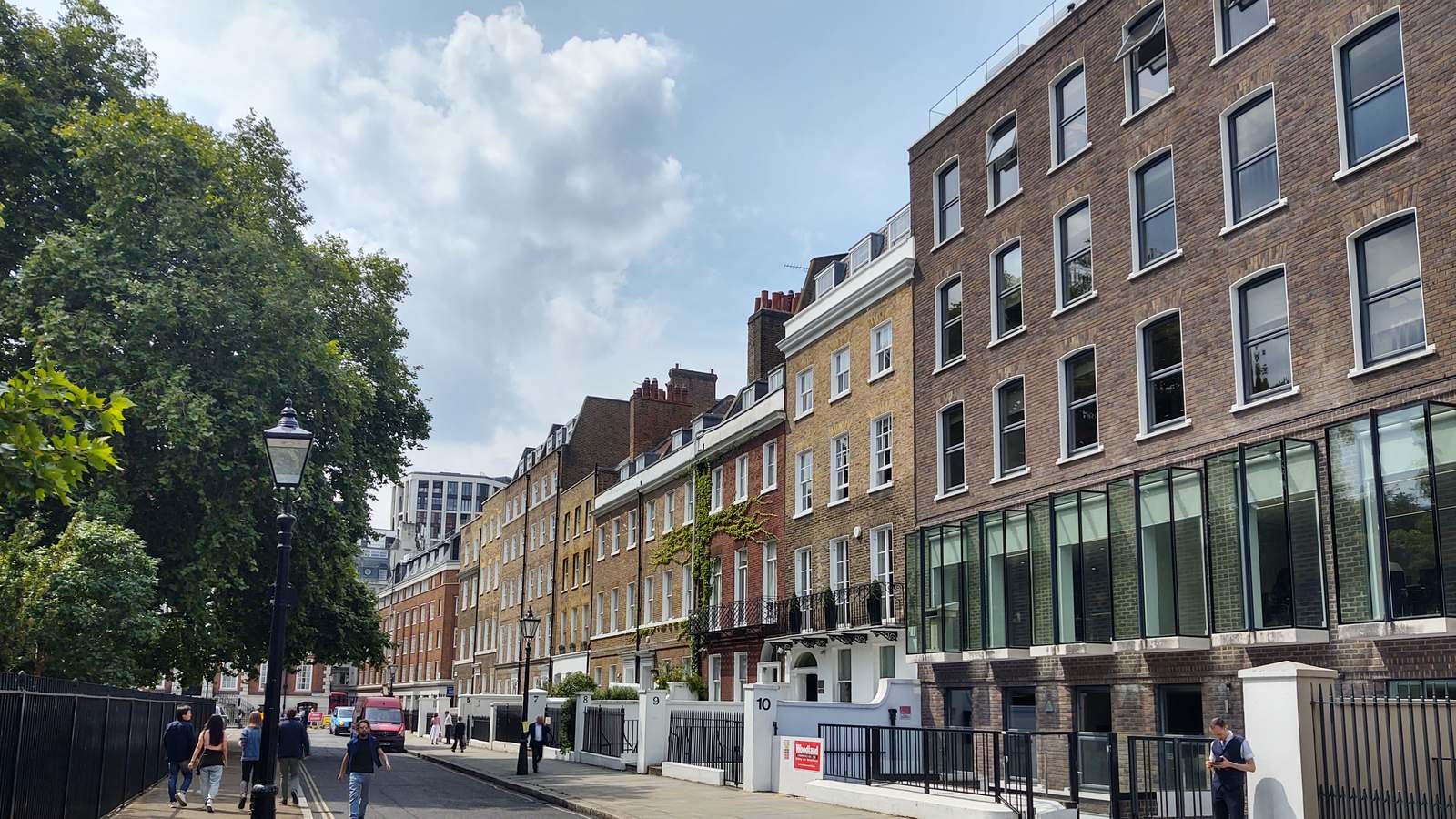 Georgian brick townhouses line the north western corner of Lincoln's Inn Fields in London, with trees and a lamppost on the left.