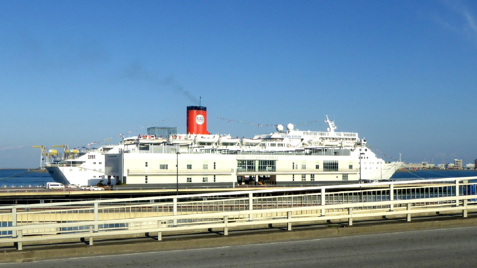 Ocean Dream cruise ship alongside a white two-story terminal at Naha New Port, Okinawa, under a clear sky.