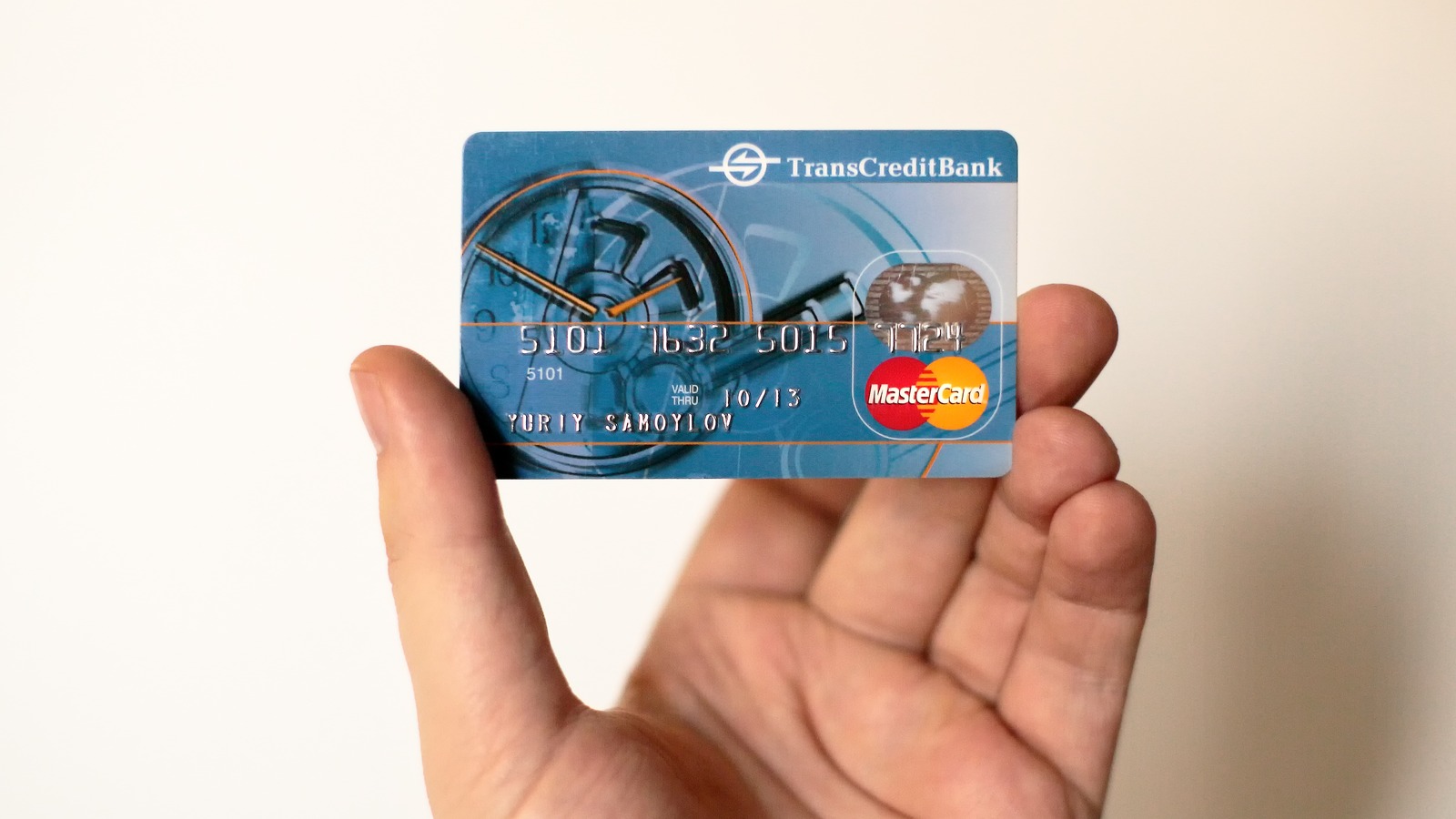 A generic payment credit card held near a payment terminal