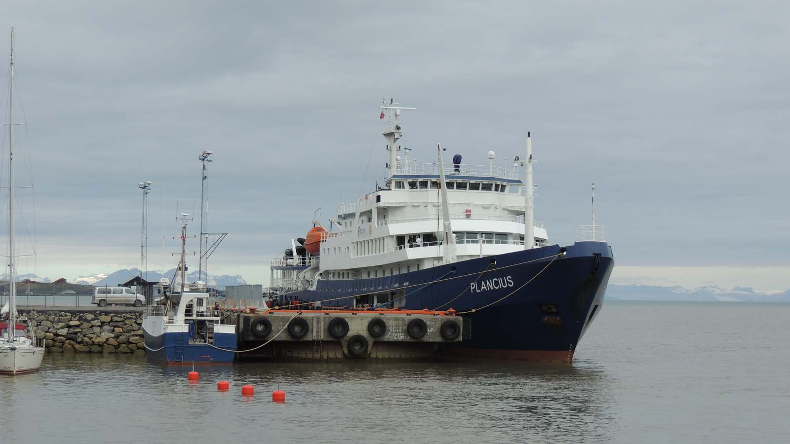 Oceanwide Expeditions ship Plancius, blue hull and white superstructure, docked at a polar harbor with the name PLANCIUS on the bow