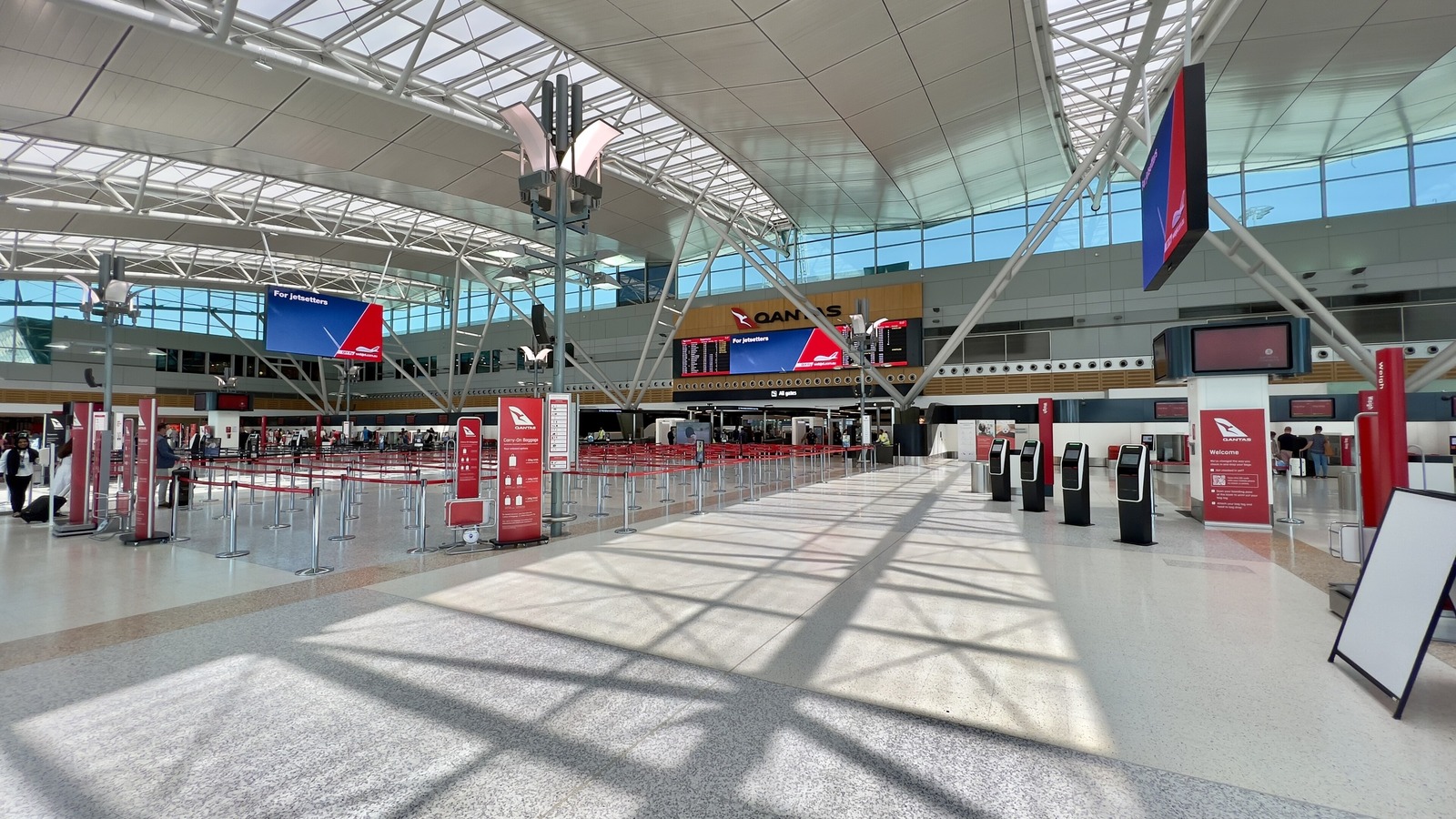 Check-in hall of Sydney Airport Terminal 3 with queue barriers and self-service kiosks in a 2023 file photo