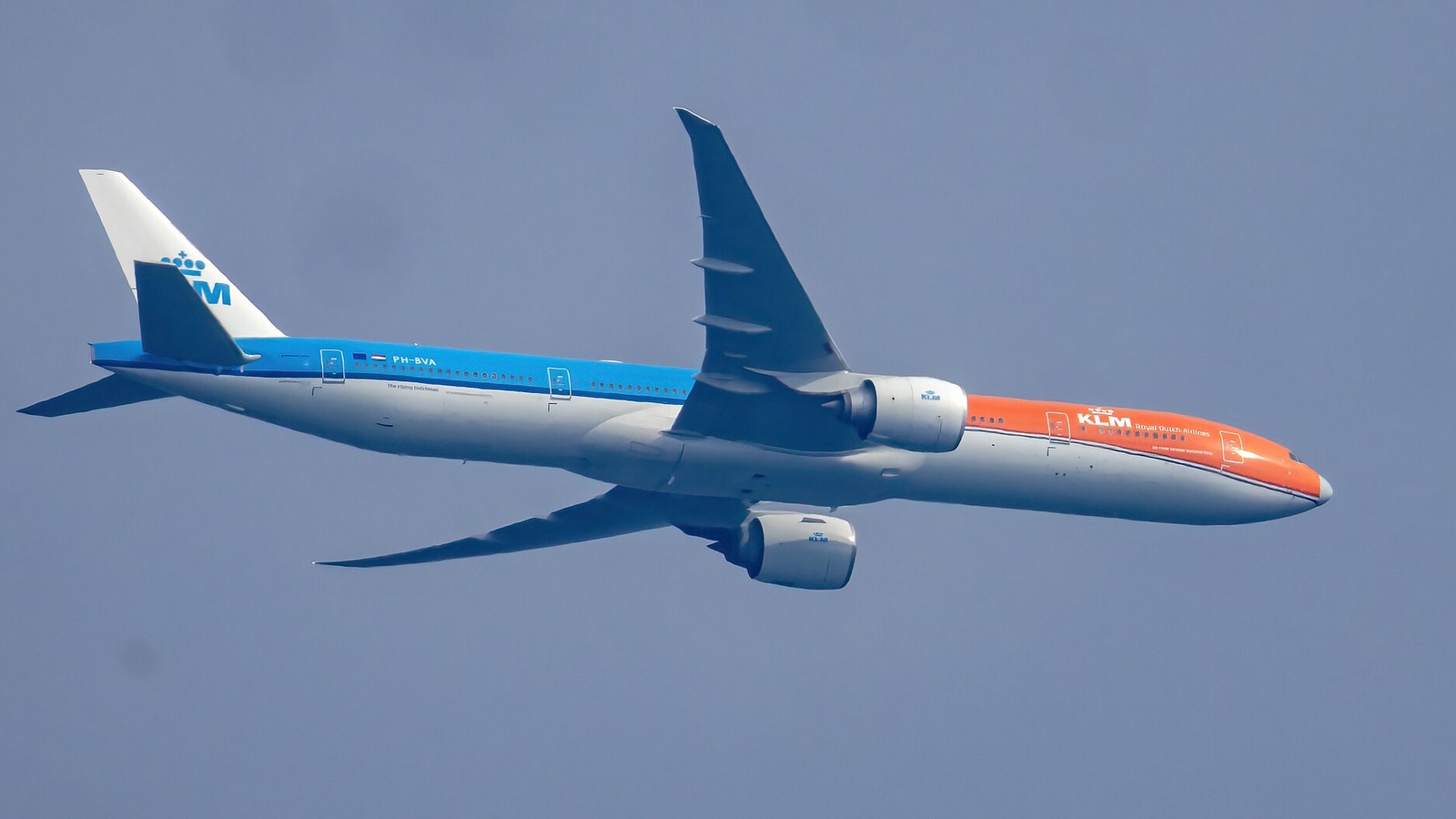 KLM Boeing 777-300ER PH-BVA in orange livery climbing against a blue sky