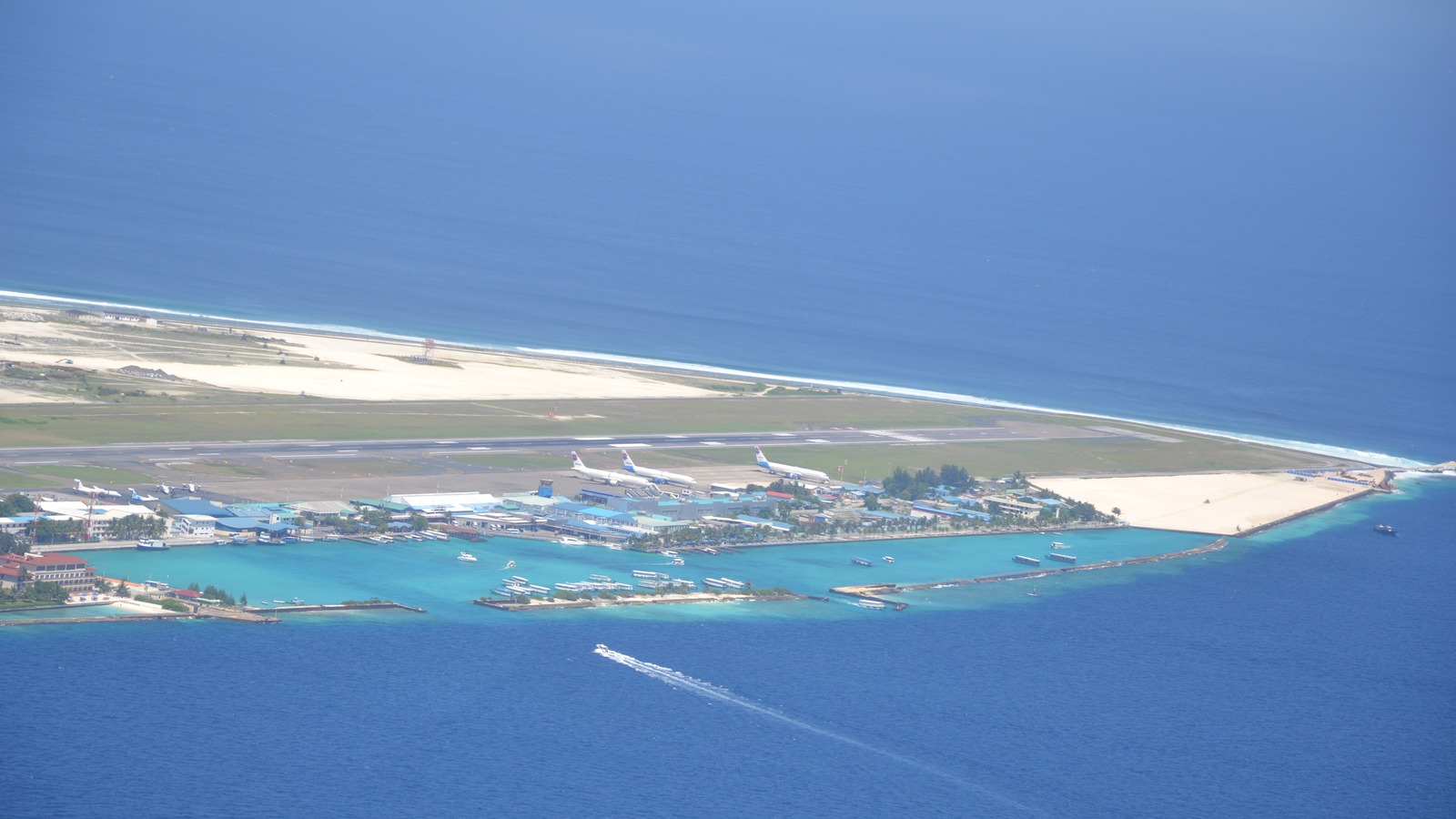 Aerial view of Velana International Airport on Hulhule island near Male, Maldives, with lagoon seaplane docks along turquoise water.