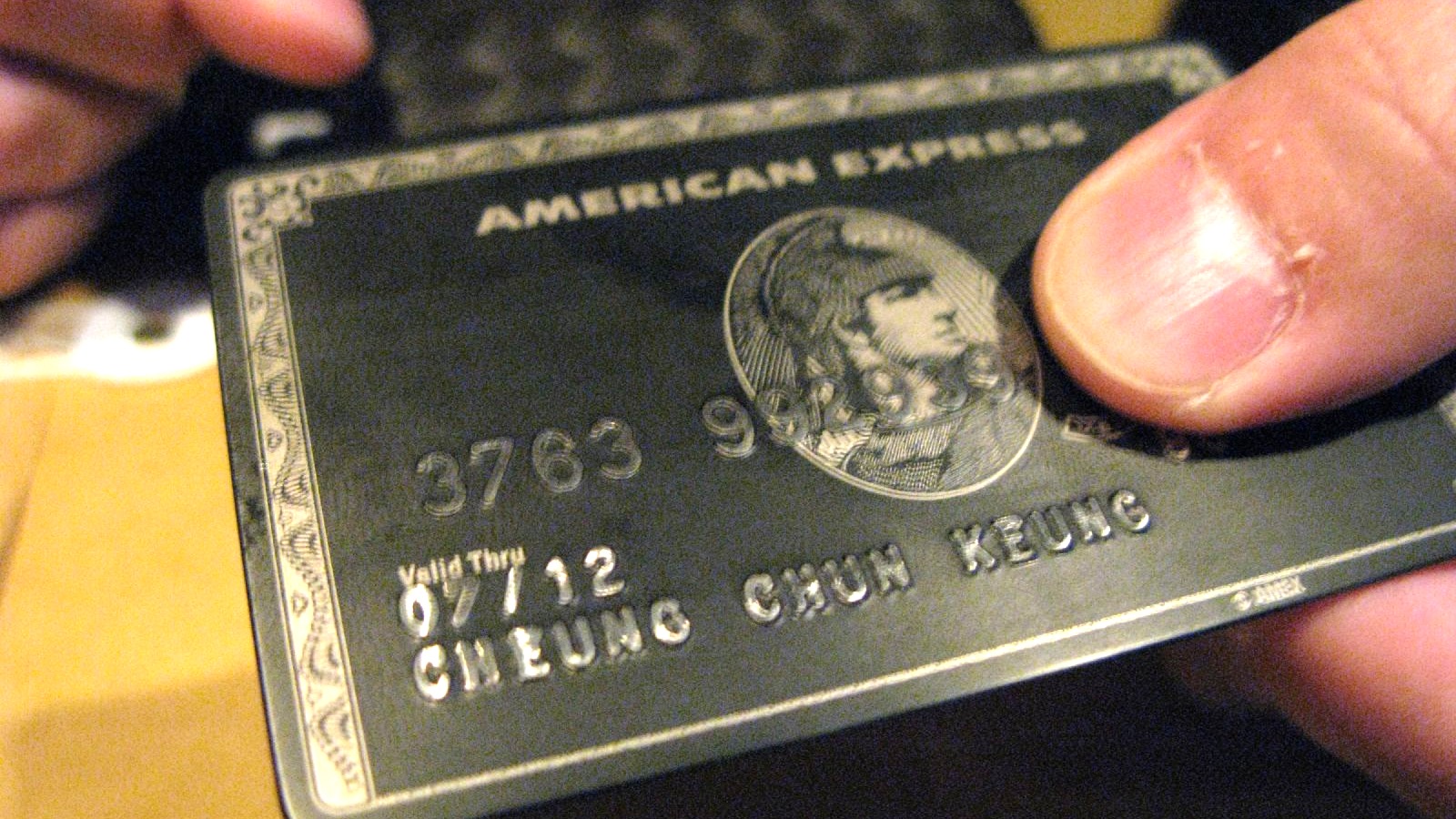 An American Express Centurion card held in a hand; the offer covers Membership Rewards earning cards generally