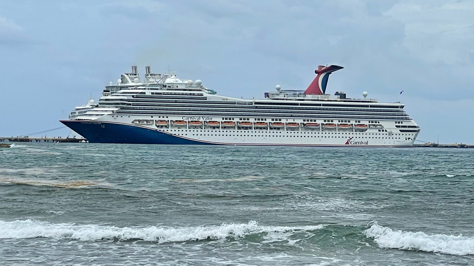Carnival Valor cruise ship at sea in daylight, exterior side view with the ship name visible on the hull
