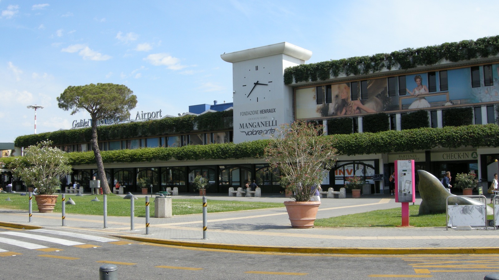 Daylight exterior of Pisa Galileo Galilei Airport terminal with CHECK-IN A signage visible on the facade
