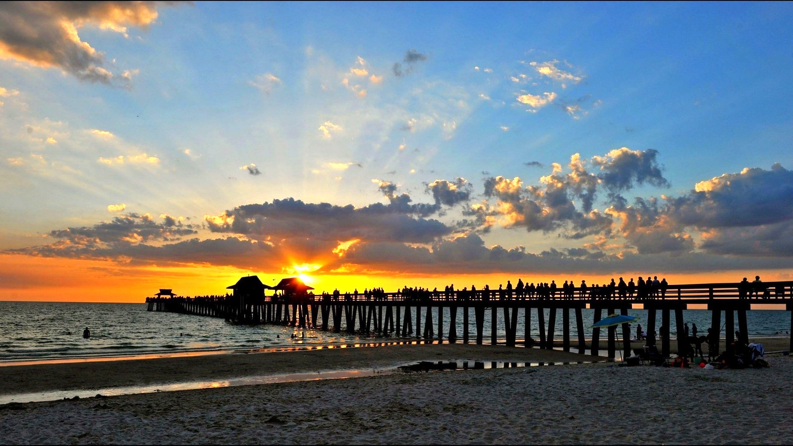Sunset over Naples Pier and beach in Naples, Florida with visitors on the pier