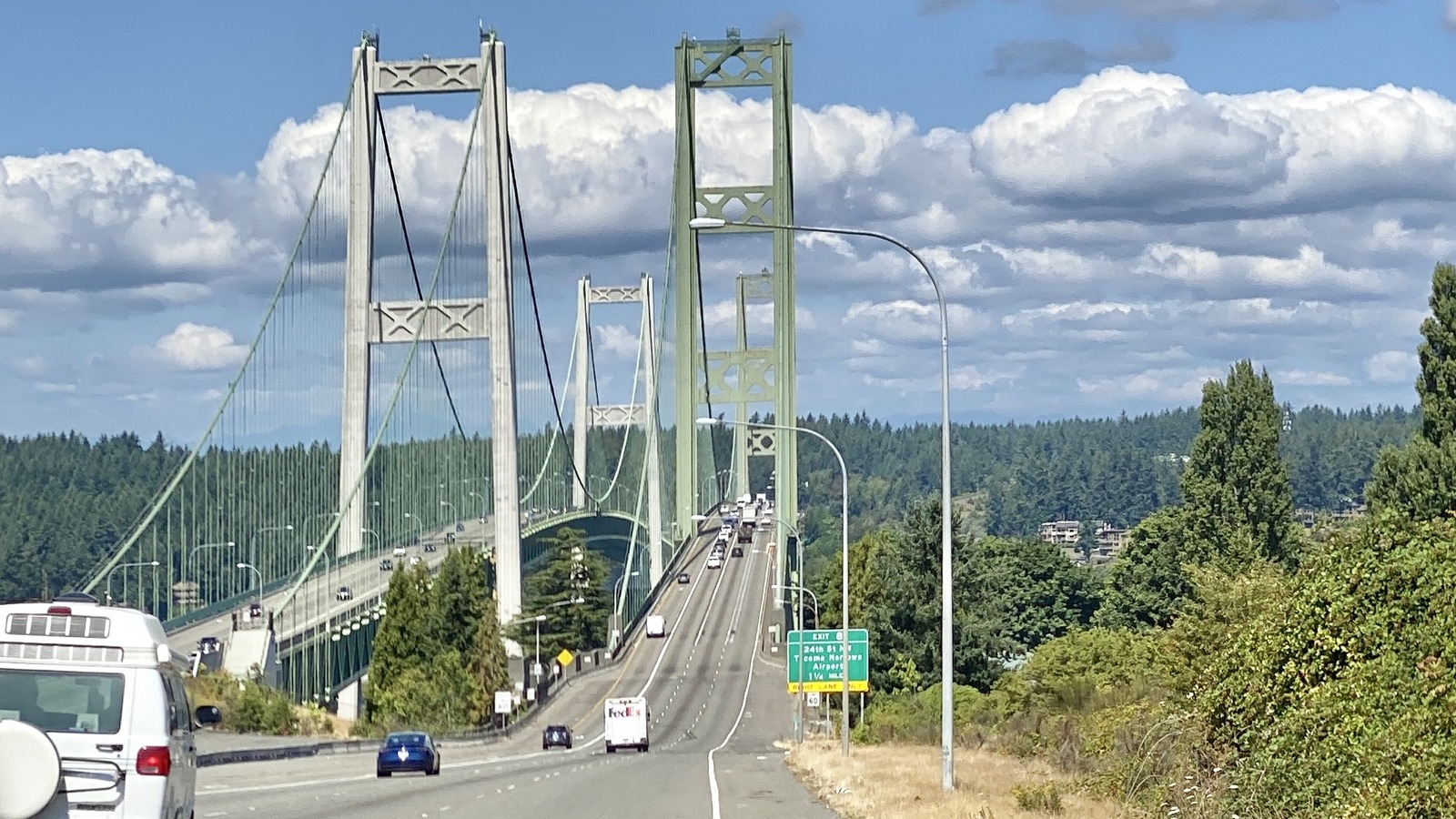 Both spans of the Tacoma Narrows Bridge carrying State Route 16 across the water under a partly cloudy sky, viewed from the Tacoma approach.