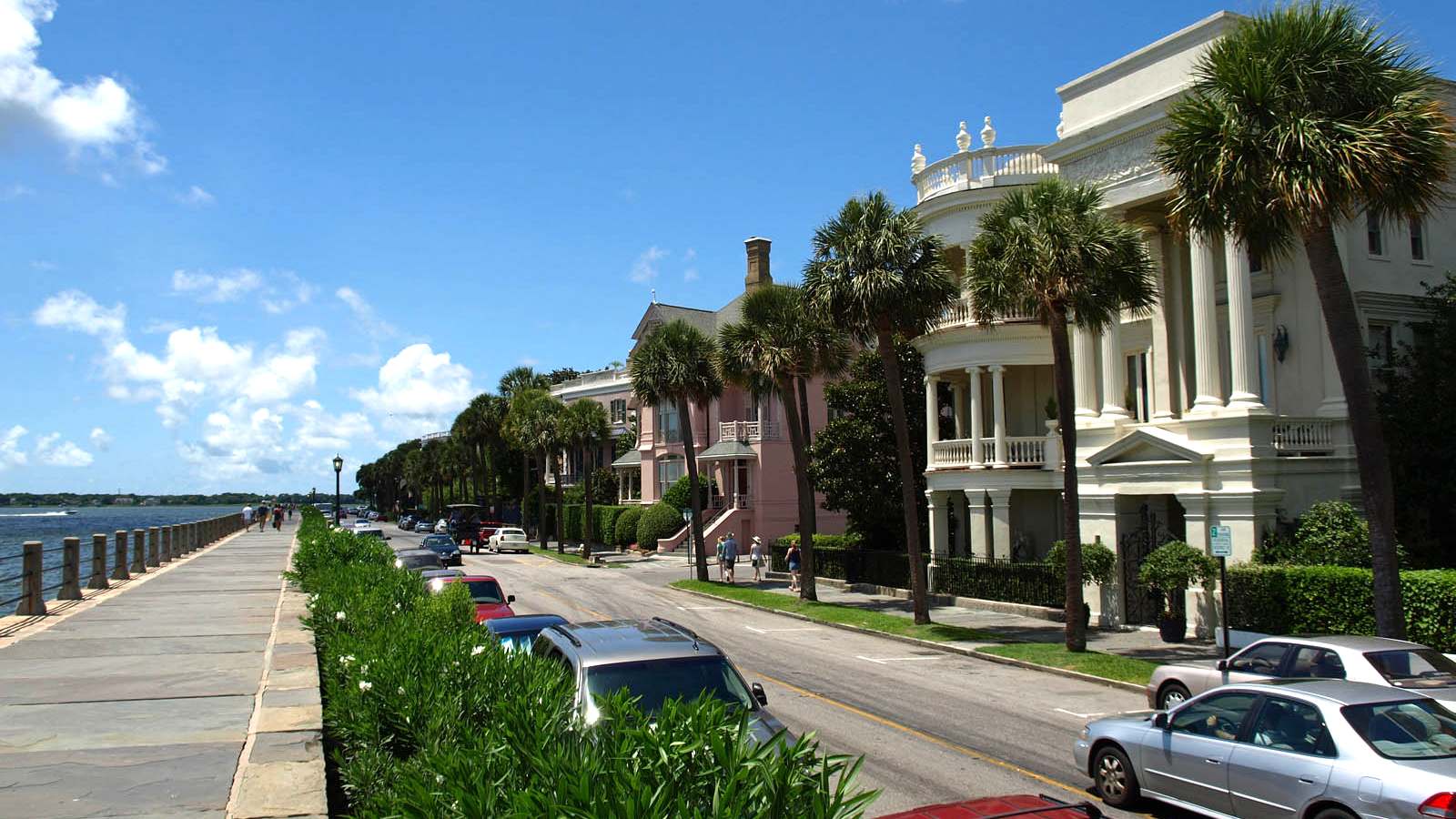 Pastel historic mansions and palmetto trees along East Battery Street beside Charleston Harbor in Charleston, South Carolina.
